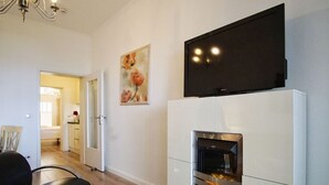 Una sala de estar moderna con chimenea, televisor de pantalla plana montado encima y comedor con sillas.