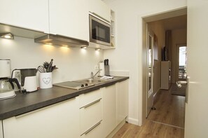 A modern kitchen with white cabinets, a microwave, and a coffee maker. - Villa Seeadler - Die Ferienwohnung in der Villa Seeadler (Binz)