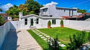 Una casa moderna de dos pisos con fachada blanca, césped cuidado y camino de entrada de grava.