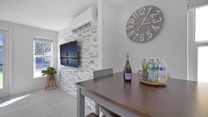 Una cocina moderna con pared de piedra, un reloj grande y una zona de comedor con mesa de madera.