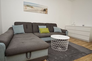 A modern living room with a sectional sofa, a round coffee table, and a minimalist white cabinet.