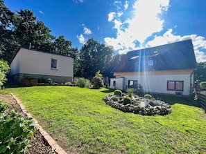A two-story house with a well-maintained lawn and a small rock garden.