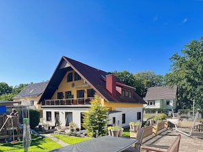 A two-story house with a sloped roof, a balcony, and a fenced backyard.