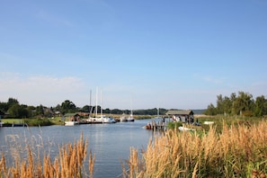 A calm river with boats docked, a small dock, and a grassy bank.