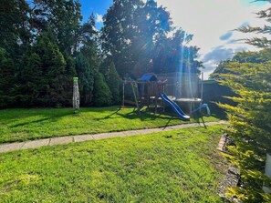 A playground with a slide and swings, surrounded by trees and a grassy area. - House in a quiet location, with free use of the pool and sauna - Ferienhus Baabe - F (Baabe)