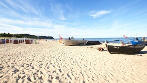 A sandy beach with boats, umbrellas, and beachgoers. - Kurparkresidenz - close to the beach, free use of the AHOI adventure pool and sauna - (Baabe)