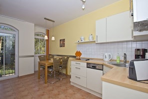 A compact kitchen with a dining area, featuring a dishwasher, a coffee machine, and a sink. - Kurparkresidenz - near the beach, free access to the AHOI adventure pool and sauna - (Baabe)