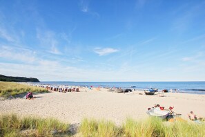 Een strand met rijen strandparasols en boten, wat een resort-achtige sfeer suggereert.