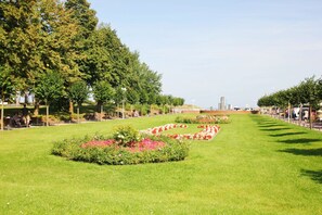 A well-maintained park with manicured lawns, flower beds, and a clear sky.