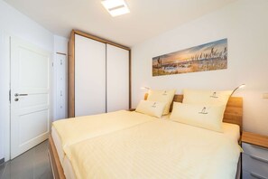 Un dormitorio con cama, mesitas de noche, un cuadro y un armario.