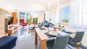 Un salón moderno con comedor, ventanas amplias y vistas al exterior.