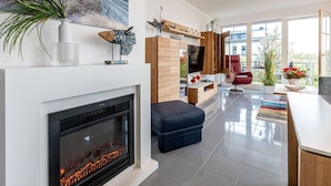 Una sala de estar moderna con chimenea, televisor y una silla roja.