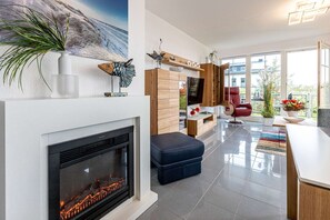 A modern living room with a fireplace, a television, and a red chair.