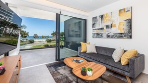 A modern living room with a grey sofa, wooden coffee table, and a large abstract painting.