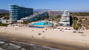 A beachfront hotel with multiple buildings, a swimming pool, and a sandy beach.