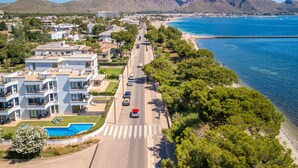 A coastal road with modern buildings, a swimming pool, and a view of the sea and mountains. - Oratge Beach Views by Interhome (Port Pollença)