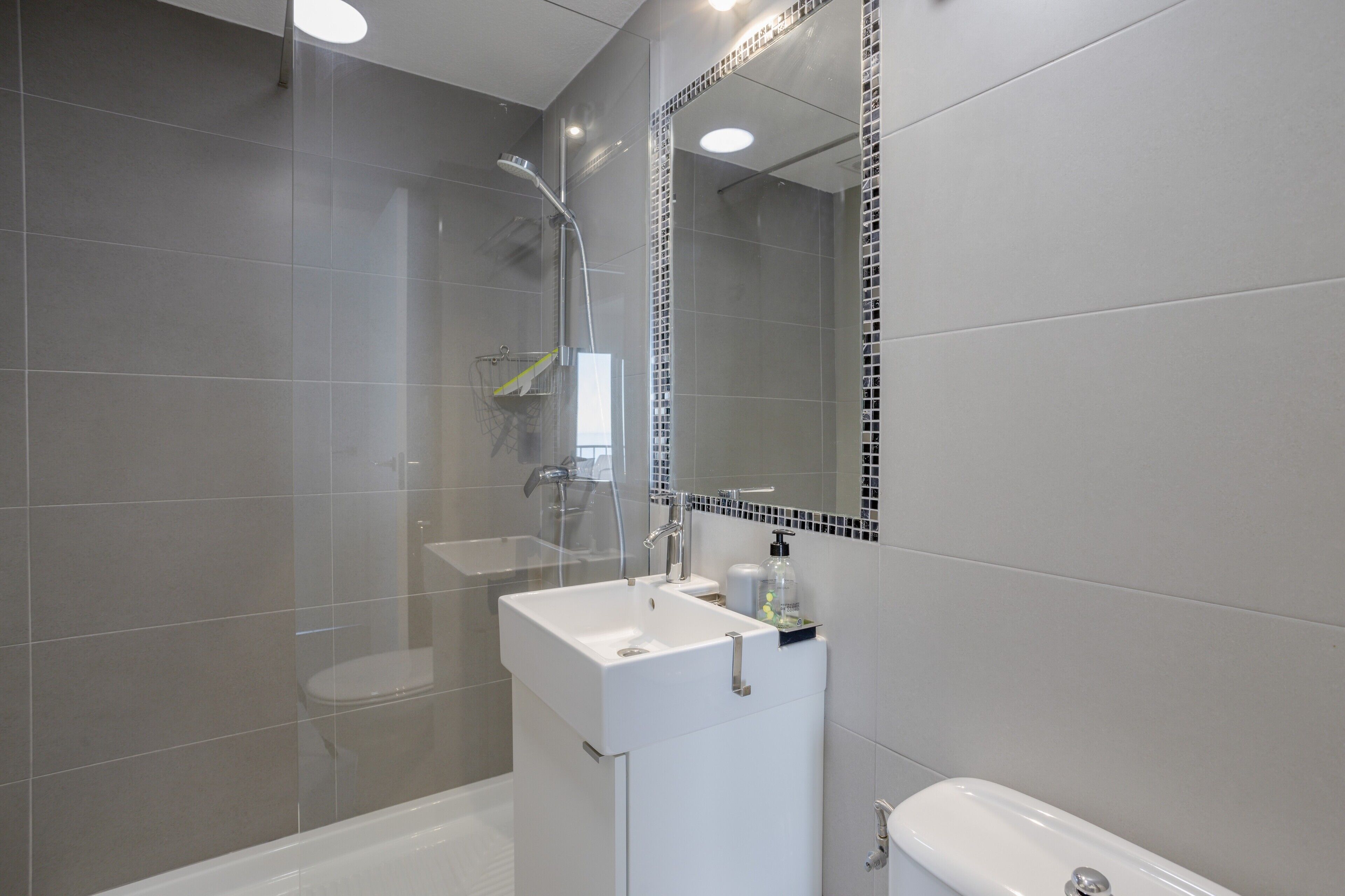 A modern bathroom with a shower, a sink, and a toilet.