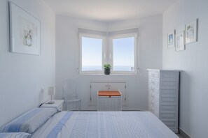Une chambre à coucher comprenant un lit, un bureau, une chaise, une commode et une fenêtre donnant sur un beau paysage.