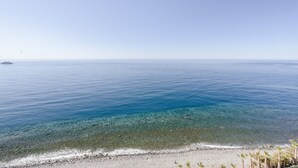 Una platja amb aigua cristal·lina, una illa a la distància i una filera de palmeres.