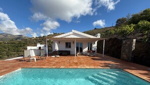 A pool with clear water, a white house with a tiled roof, and a view of hills in the background. - Villa 'Casa Livernana' with Sea View, Wi-Fi and Air Conditioning (Cómpeta)