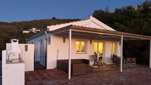 A house with a patio, outdoor seating, and a kitchen area. - Villa 'Casa Livernana' with Sea View, Wi-Fi and Air Conditioning (Cómpeta)