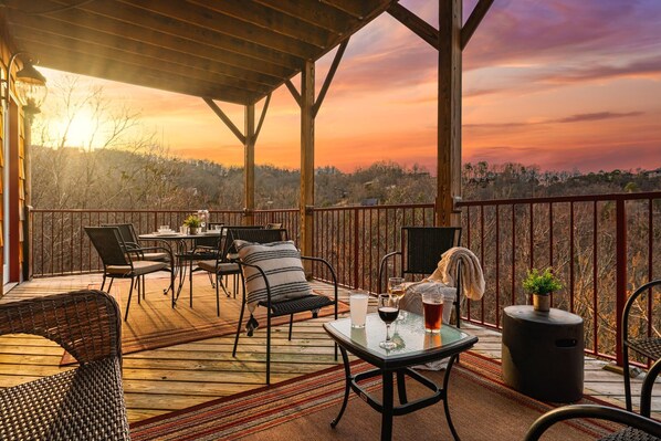 A covered outdoor seating area with tables and chairs, overlooking a scenic landscape.