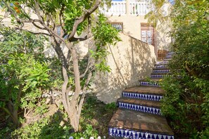 Un escalier aux marches bleues et blanches, formant un motif, mène à un bâtiment doté d’un balcon blanc.