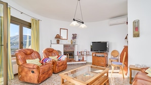 A living room with leather sofas, a glass coffee table, a fireplace, a television, and a view of the outdoors. - "Villa María" with Sea View, Garden, Balcony & Wi-Fi (Almunecar)