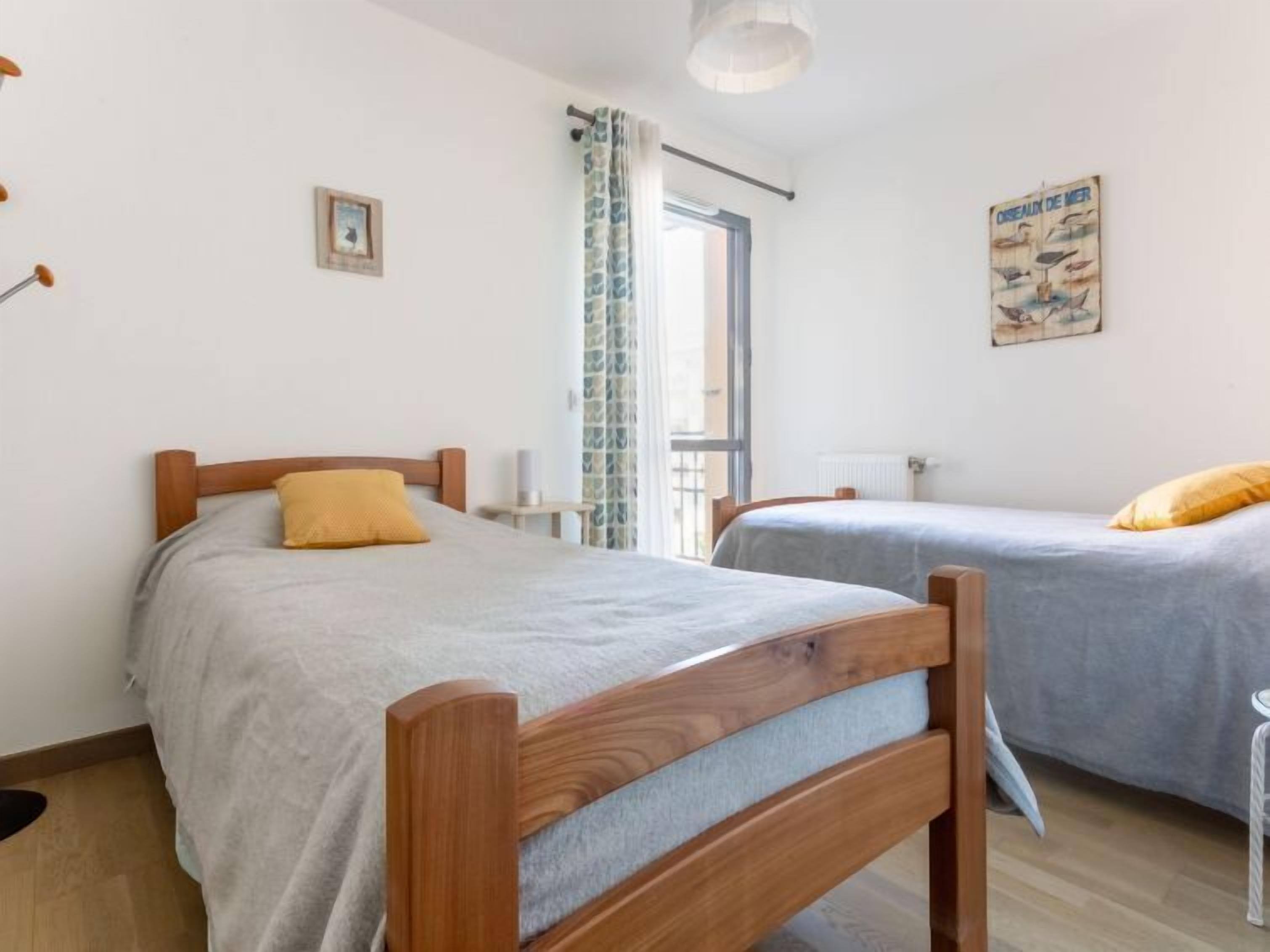 Ein Zimmer mit zwei Holzbetten, einem Vorhangfenster, einem Heizkörper und einem Poster an der Wand.
