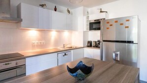 Una cocina moderna con armarios blancos, electrodomésticos de acero inoxidable y encimera de madera.