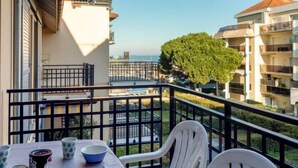 Un balcón con mesa y sillas, con vista a una zona residencial y al mar.