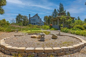 A landscaped garden with a stone pathway, a stone lantern, and a gazebo.