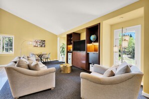 A living room with a sofa set, a coffee table, a flat-screen TV, and a globe on a shelf.