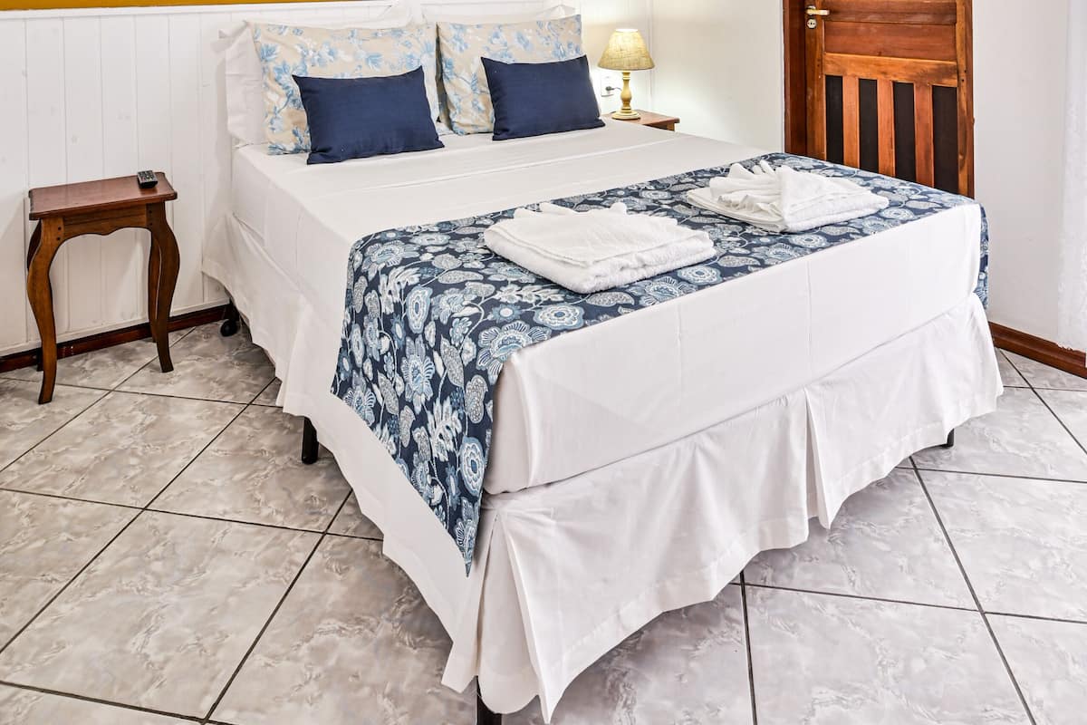 A bedroom with a bed, a wooden door, a ceiling fan, and a wall with fish decals.