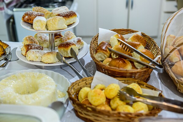 A buffet with various baked goods including bread, rolls, and pastries.