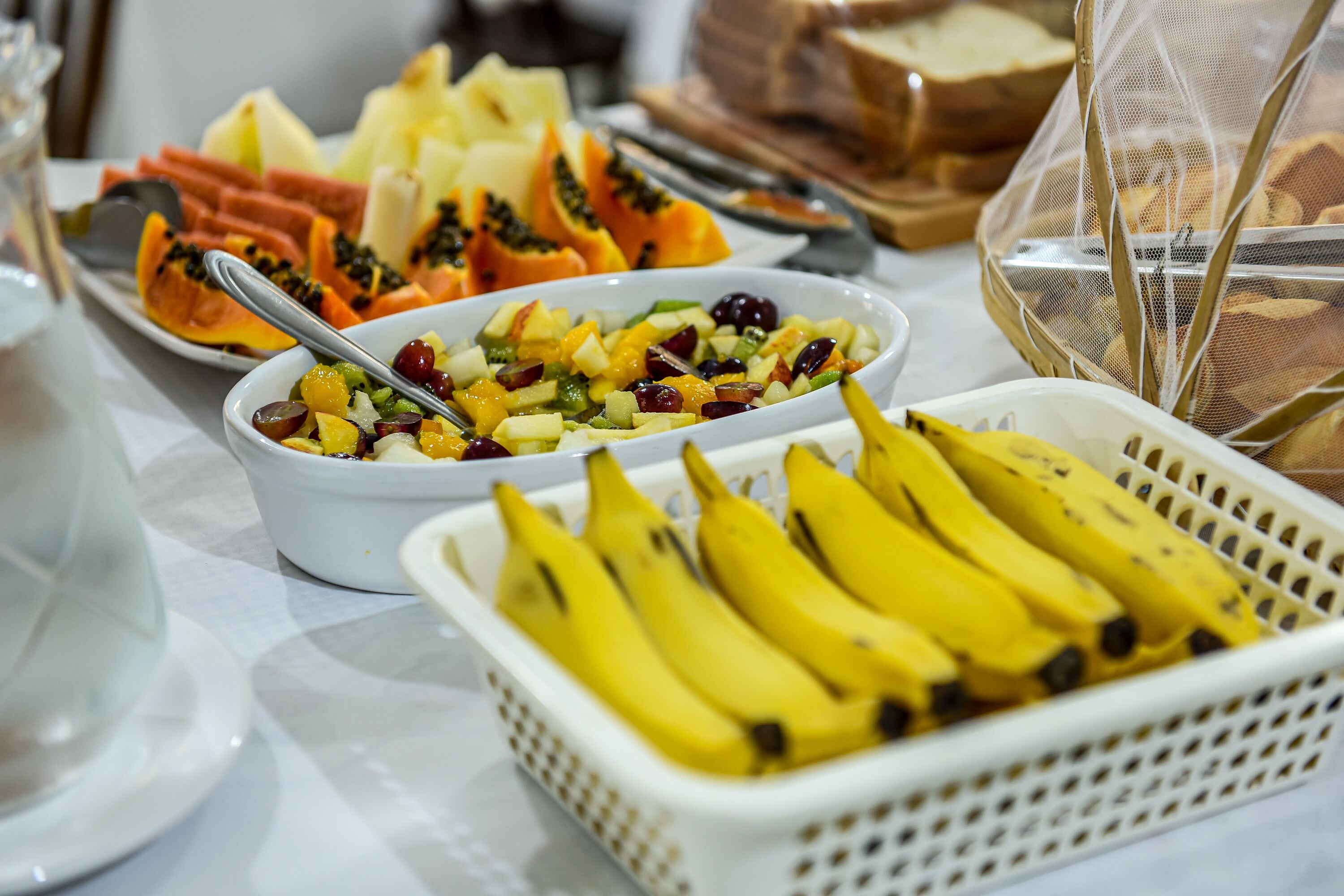 Una mesa de buffet con diversas frutas y un cesto de plátanos.