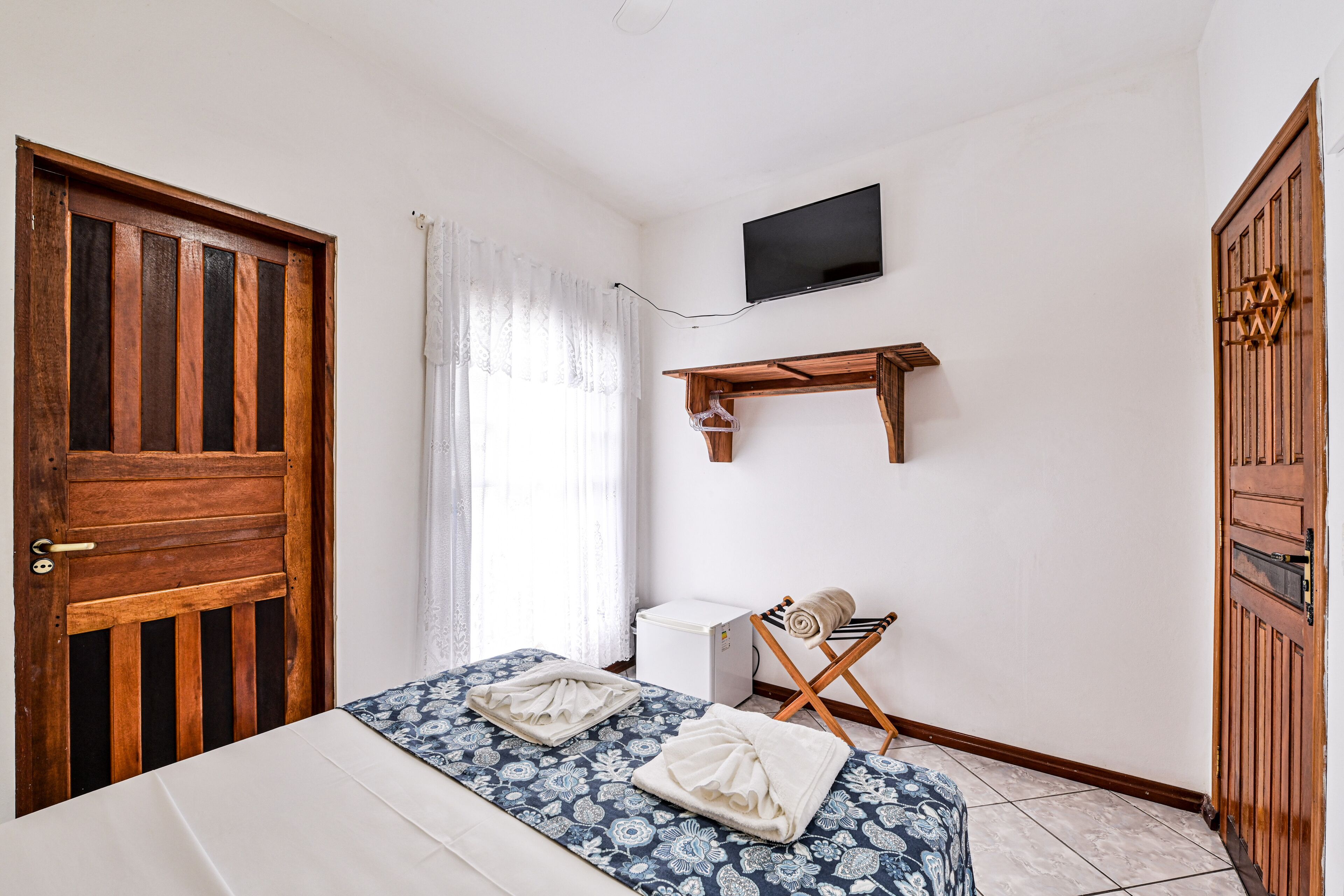 Un dormitorio con una cama, un televisor montado en la pared y un armario de madera.