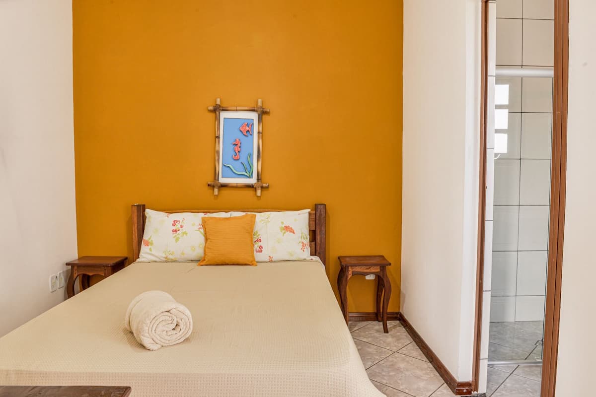 A hotel room with a bed, a framed picture on the wall, and a towel on the bed.