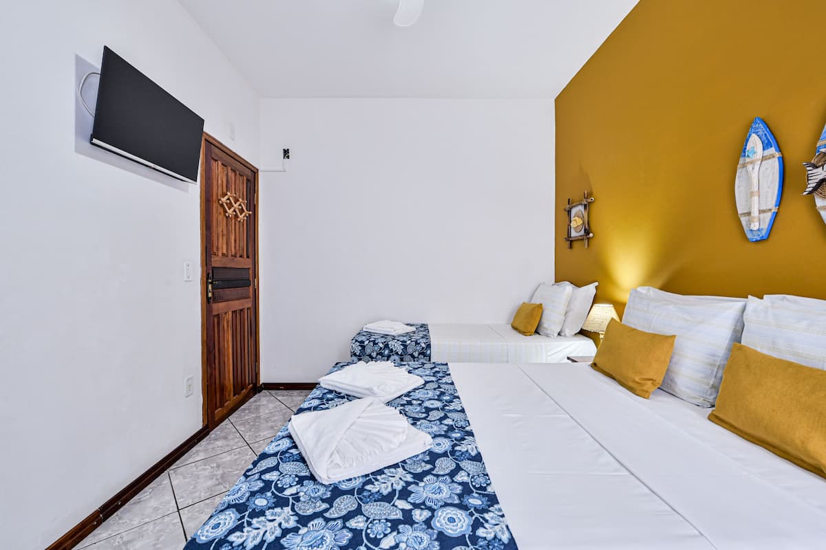 A hotel room with a bed, a sofa, a TV mounted on the wall, and a wooden door.