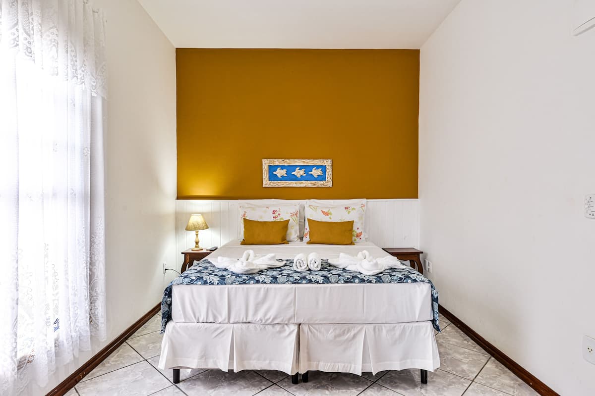 A hotel room with a bed, a nightstand, a lamp, and a wall-mounted sign.