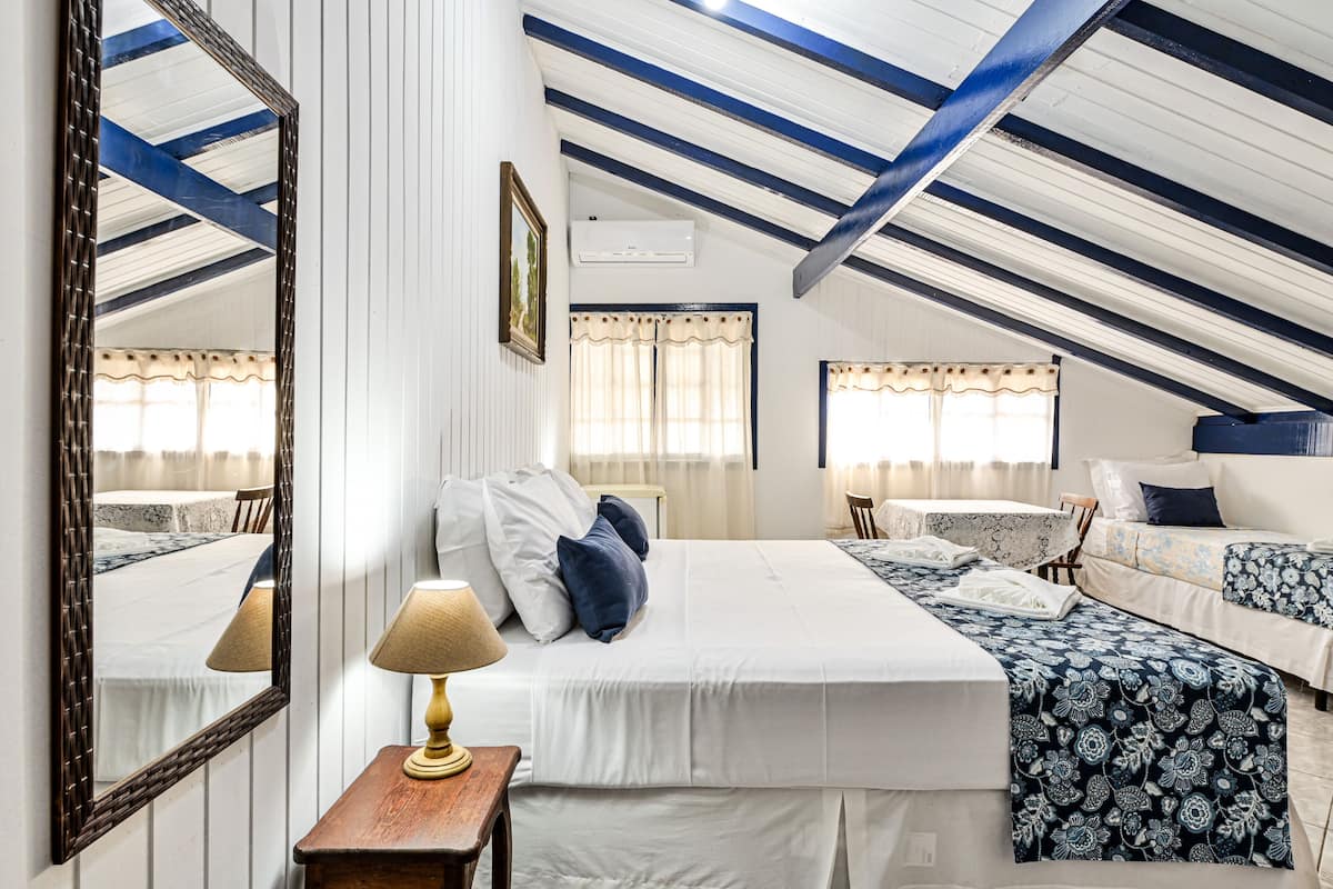 A bedroom with a large bed, bedside tables, a mirror, and a ceiling with exposed beams.