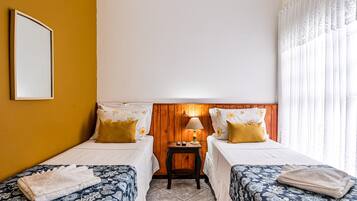 Una habitación de hotel con dos camas, una mesita de noche con lámpara y un espejo en la pared.