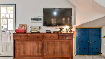 A wooden cabinet with drawers, a television mounted on the wall, and a blue door.