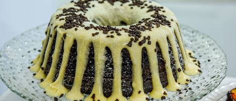 A bundt cake with chocolate drizzle and sprinkles on a glass plate.