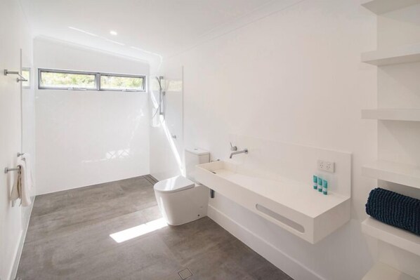 Un baño moderno con un ventanal grande, un lavabo blanco y un inodoro.