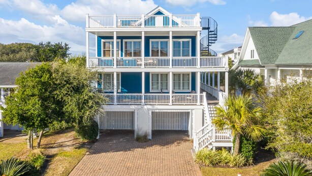 A two-story beachfront house with a balcony, a covered porch, and a small staircase. - Luxury, Oceanview Beach Home w/ Private Pool & Outdoor Kitchen, Hot Tub, Rooftop Deck, & Elevator! (Isle Of Palms)