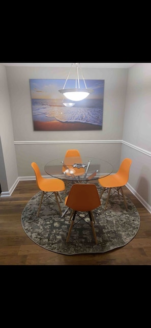Enjoy meals in this dining area with a round table and four chairs, accompanied by a beautiful seascape painting.
