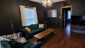 Un salon avec un canapé de couleur foncée, une table basse en bois et un téléviseur à écran plat.