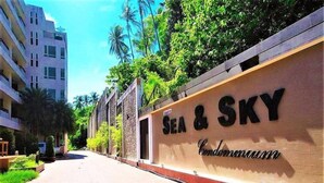 A pathway leading to a building with a sign reading "SEA & SKY Condominium". - Sea and Sky Condominium by Lofty (Karon)