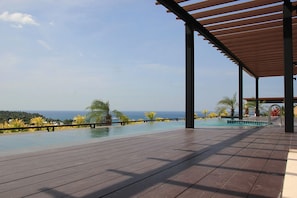 A wooden deck with a pool and a view of the ocean.